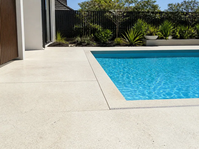 Pale honed concrete surrounding a backyard pool